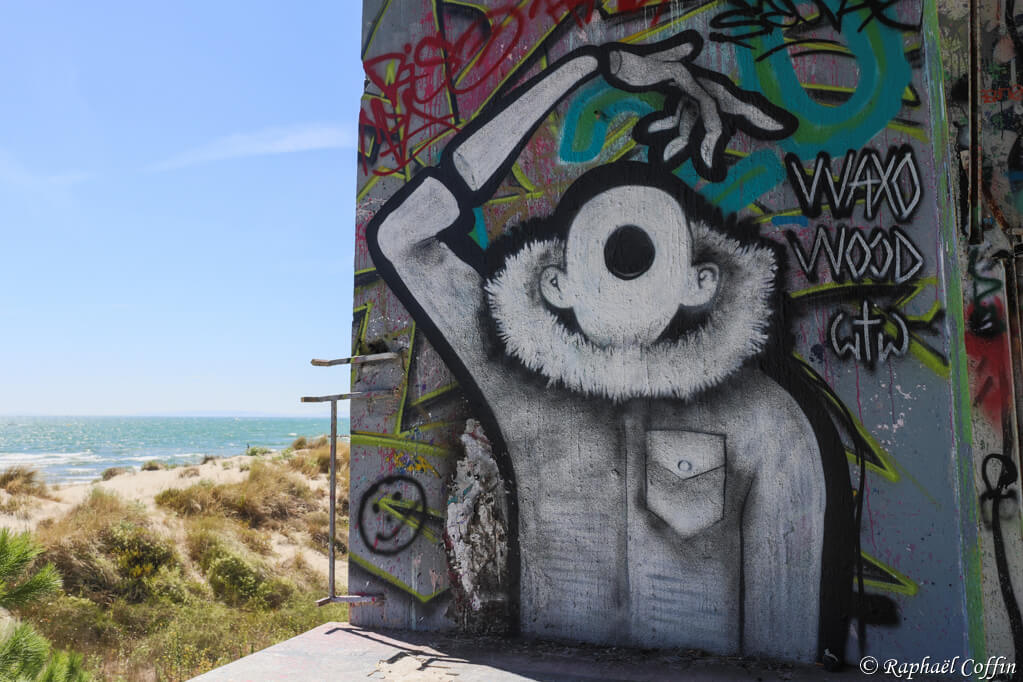 Hôpital abandonné vu de la plage et d'un graffiti