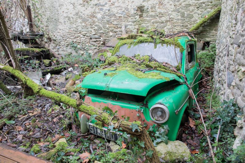 Vieille voiture verte recouverte de mousse abandonnée