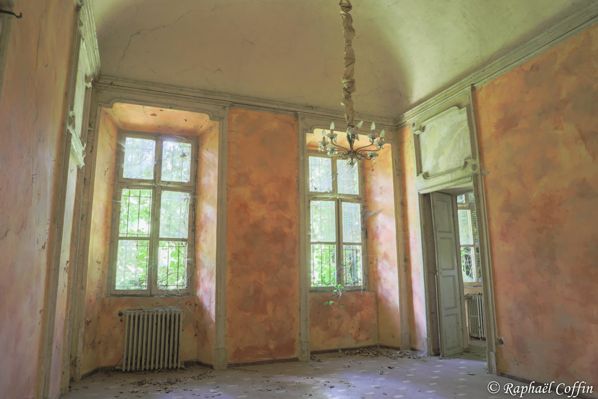 Deuxième pièce de la villa Mint avec des murs oranges et un lustre