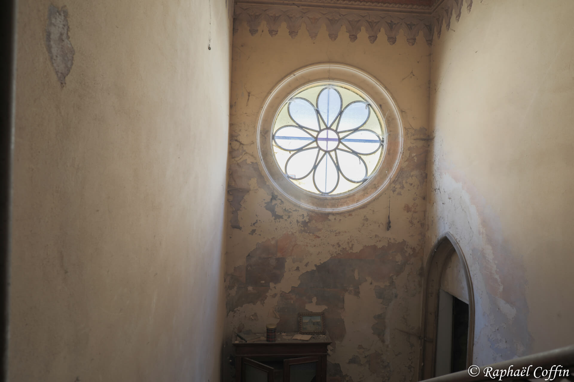 Petit escalier avec une rosace en guise de fenêtre.