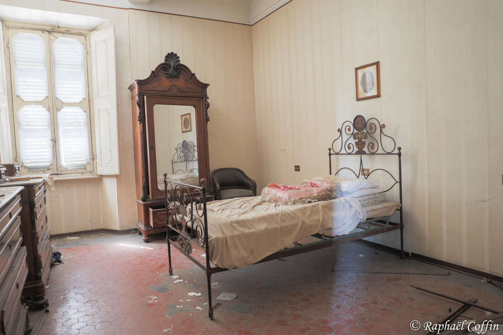 Petite chambre avec un ancien lit en fer et une commode.